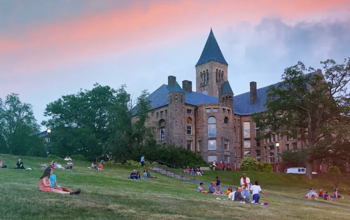 a castle and lawn with students at cornell