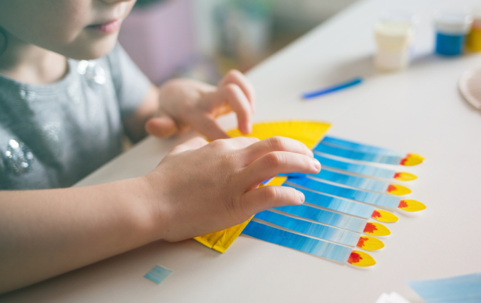 Kid making a craft menorah with eight lighted candles.